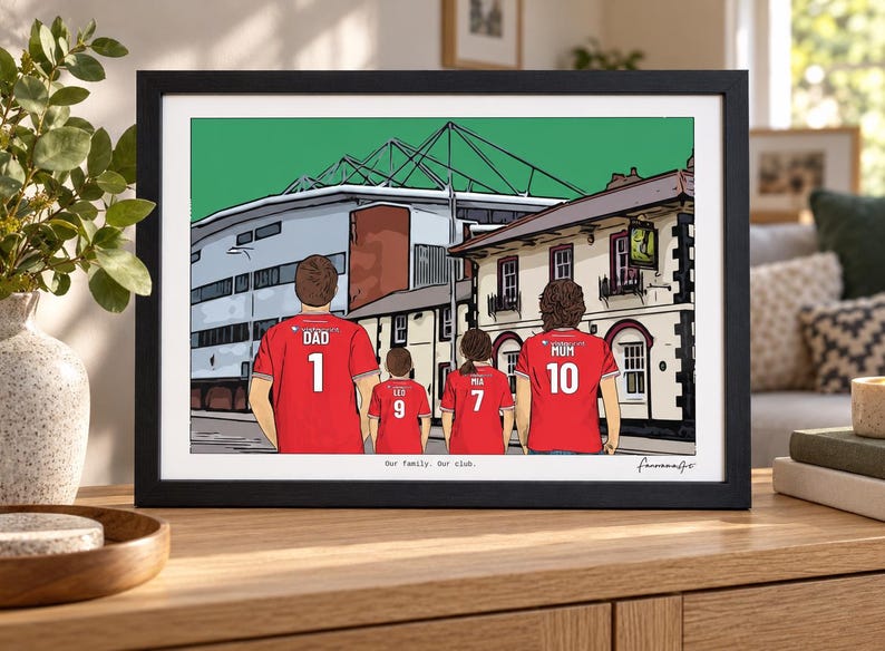 Pu&ograve; includere: Un'illustrazione incorniciata di quattro persone che indossano maglie da calcio rosse con numeri e nomi sul retro, davanti a uno stadio e un edificio. Il testo "Our family. Our club." &egrave; stampato in fondo all'opera.