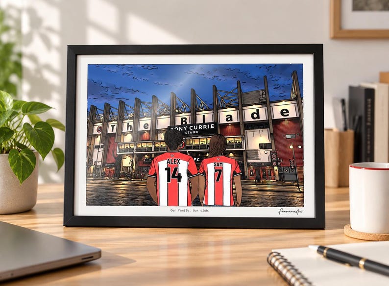 May include: A framed digital illustration of two people wearing red and white striped soccer jerseys with the names ALEX 14 and SAM 7 on the back, standing before a stadium with a sign reading The Blade and Tony Currie Stand.