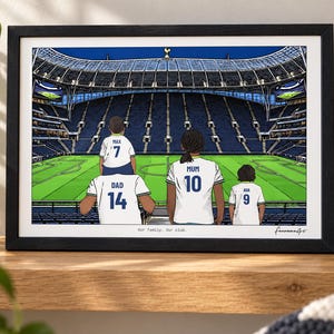 Puede incluir: Una ilustraci&oacute;n enmarcada de un estadio de f&uacute;tbol con cuatro personas vistiendo camisetas blancas con nombres y n&uacute;meros en la espalda. El texto "Our family. Our club." est&aacute; impreso en la parte inferior central, con una firma en la esquina inferior derecha.