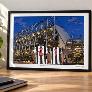 May include: A framed art print depicting a stadium at night with two individuals in black and white striped jerseys standing in the foreground. The jerseys feature the names Alex and Sam with the numbers 14 and 7. Text reads Our Family. Our club.