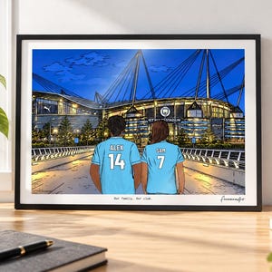 May include: A framed digital illustration depicting two individuals from behind, wearing light blue soccer jerseys with the names ALEX and SAM and numbers 14 and 7, standing before the Etihad Stadium at night. The text reads Our family. Our club.