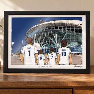 Puede incluir: Una ilustraci&oacute;n enmarcada de cuatro personas vistas desde atr&aacute;s con camisetas de f&uacute;tbol blancas con n&uacute;meros y nombres en azul, frente a un gran estadio. Las camisetas dicen DAD 1, LEO 9, MIA 7 y MUM 10. El texto Our family. Our club. aparece impreso debajo.