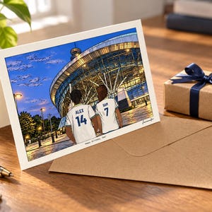 May include: A greeting card featuring a digital illustration of two people from behind, wearing white sports jerseys with the names ALEX 14 and SAM 7, standing before a large illuminated stadium at dusk. The text Happy Birthday, Dad! is printed below.