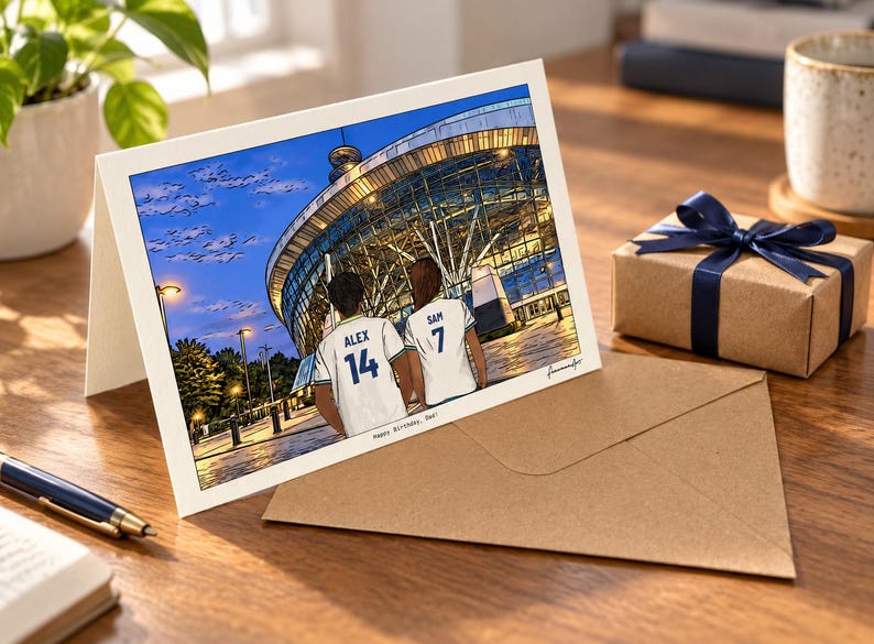 May include: A greeting card featuring a digital illustration of two people from behind, wearing white sports jerseys with the names ALEX 14 and SAM 7, standing before a large illuminated stadium at dusk. The text Happy Birthday, Dad! is printed below.