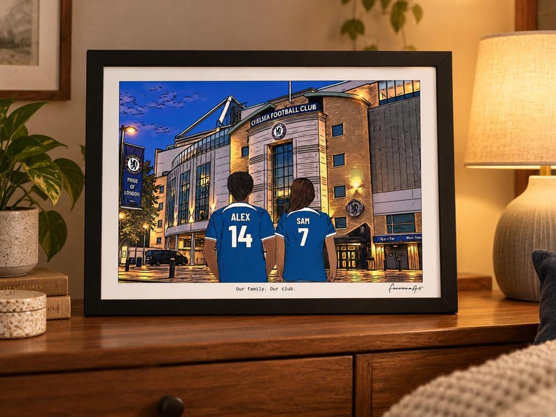 Puede incluir: Una ilustraci&oacute;n enmarcada de dos personas con camisetas azules del Chelsea Football Club con los nombres ALEX y SAM y los n&uacute;meros 14 y 7 en la espalda, frente al estadio. El texto Our family. Our club. est&aacute; impreso en la parte inferior.
