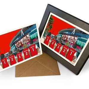 May include: A personalized card featuring a cartoon illustration of a family of five wearing red shirts with numbers on the back, standing in front of a stadium. The stadium is red and has a large screen showing a football game. The text on the shirts reads "Mya 1", "Maxwell 2", "Isaac 3", "Mummy 2", and "Daddy 1".