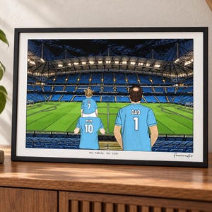 May include: A framed illustration of a soccer stadium with three people wearing light blue jerseys. One person has a child on their shoulders. The jerseys feature the text MUM 10, DAD 1, and a child's jersey with 7. The text Our family. Our club. is below.