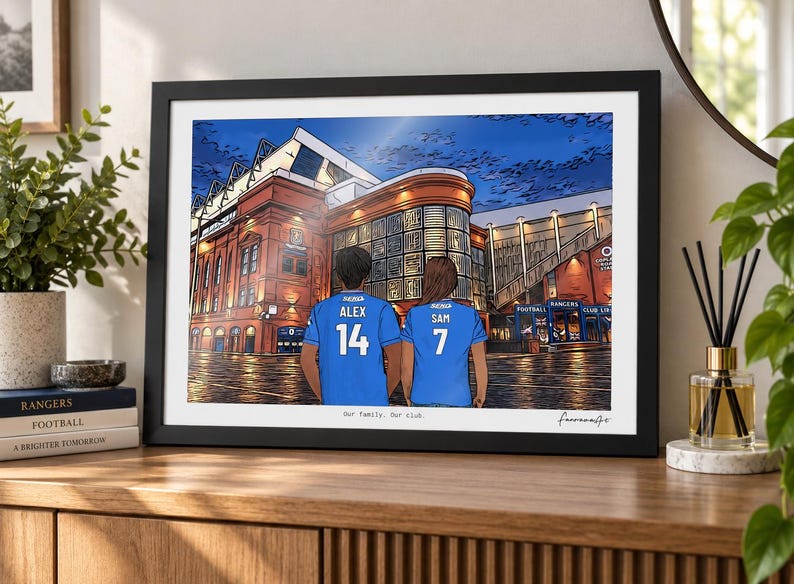 May include: A framed digital illustration depicting two people from behind wearing blue soccer jerseys with the names ALEX and SAM and numbers 14 and 7, standing before a large brick stadium. The text Our family. Our club. is printed below.