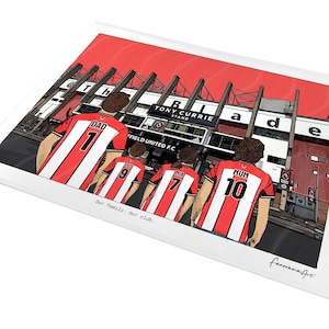 May include: A digital illustration print featuring four people from behind wearing red and white striped soccer jerseys with names and numbers, standing before the Tony Currie Stand at Sheffield United F.C. stadium. Text reads: Our family. Our club.