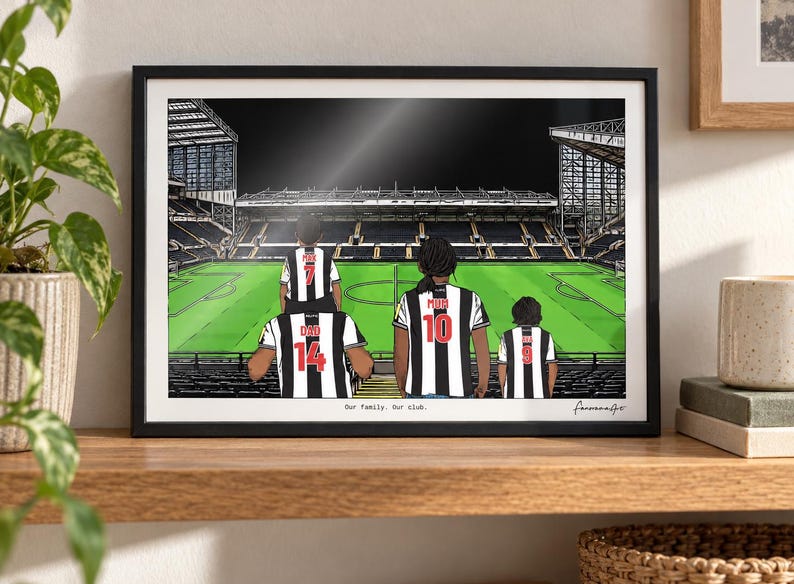 May include: A framed illustration of a family of four wearing black and white striped soccer jerseys with red numbers and names on the back, standing in a stadium. The text "Our family. Our club." is printed at the bottom of the artwork.