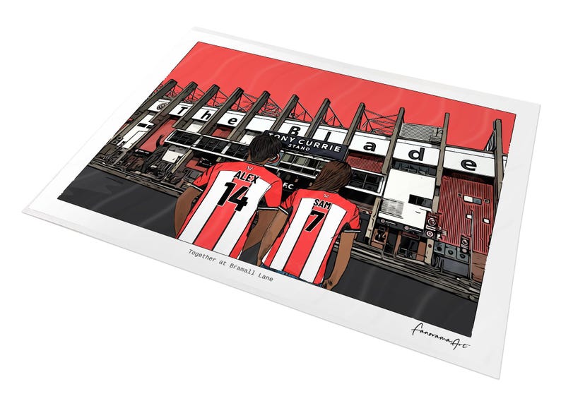 May include: A rectangular art print featuring a cartoon illustration of two people in red and white striped soccer jerseys with the names ALEX 14 and SAM 7, standing before the Tony Currie Stand at Bramall Lane, with the text Together at Bramall Lane.