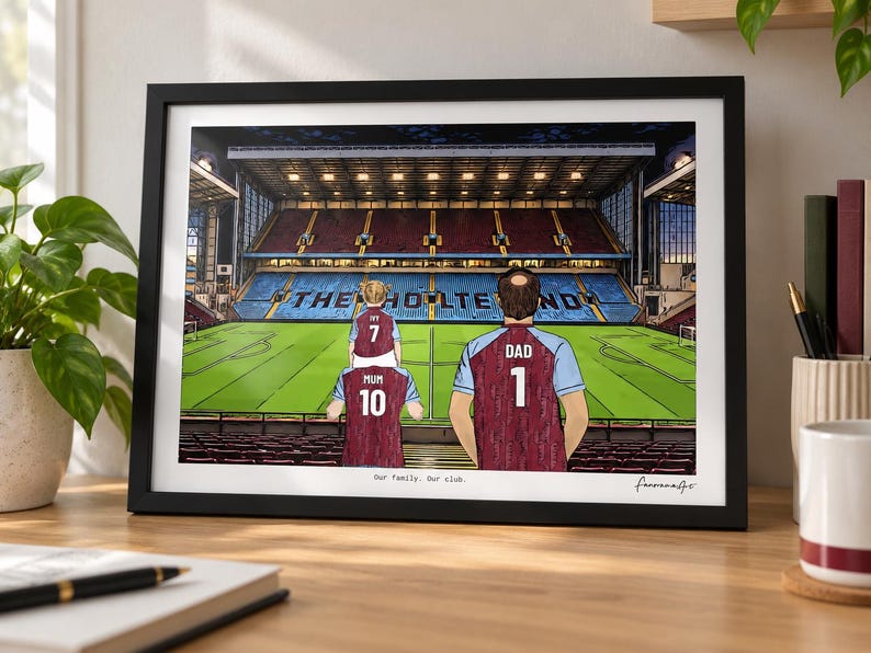 May include: A framed illustration of a soccer stadium interior with the text THE HOLTE END visible on the seating. Three figures in claret and blue jerseys stand in the foreground, with the text Our family. Our club. printed below the image.
