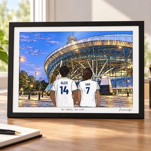 Puede incluir: Una ilustraci&oacute;n enmarcada de dos personas vistas desde atr&aacute;s con camisetas de f&uacute;tbol blancas con los nombres Alex y Sam y los n&uacute;meros 14 y 7, frente a un gran estadio de cristal al atardecer. El texto Our family. Our club. aparece abajo.