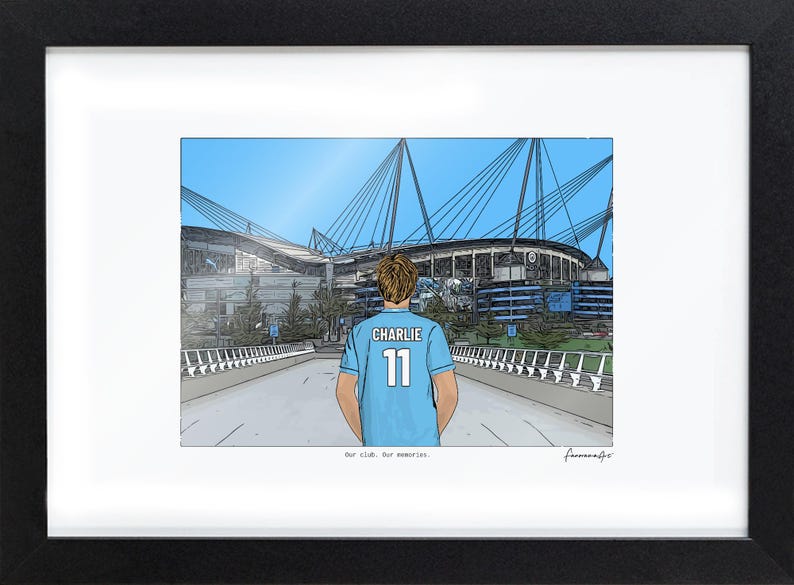 May include: A framed illustration of a stadium with a person in a light blue jersey with the name CHARLIE and the number 11 on the back. The text Our club. Our memories. is printed below the illustration in a black frame with a white mat.