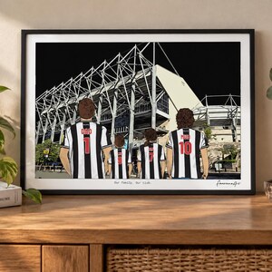 May include: A framed art print depicting four people from behind, wearing black and white striped soccer jerseys with numbers and names, standing before a large stadium. The text "Our family. Our club." is printed at the bottom of the illustration.