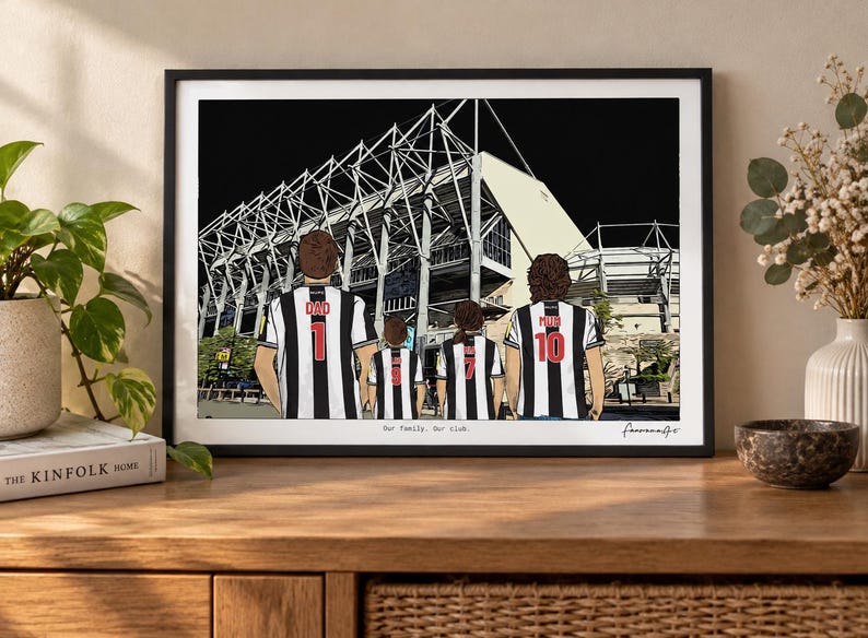 May include: A framed art print depicting four people from behind, wearing black and white striped soccer jerseys with numbers and names, standing before a large stadium. The text "Our family. Our club." is printed at the bottom of the illustration.