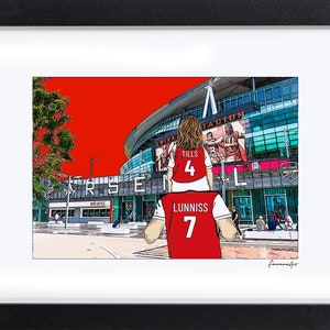 May include: A digital illustration of a father and daughter wearing red Arsenal soccer jerseys with the names "Lunniss" and "Tills" on the back. The daughter is sitting on the father's shoulders. The Emirates Stadium is in the background.