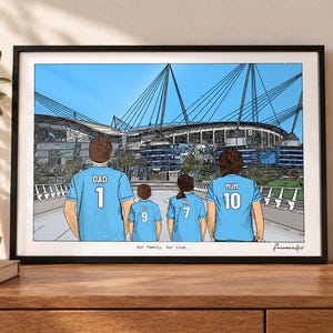 May include: A framed illustration of four people from behind wearing light blue soccer jerseys with names and numbers, standing before a large stadium. The text reads "Our family. Our club." and includes a signature in the bottom right corner.