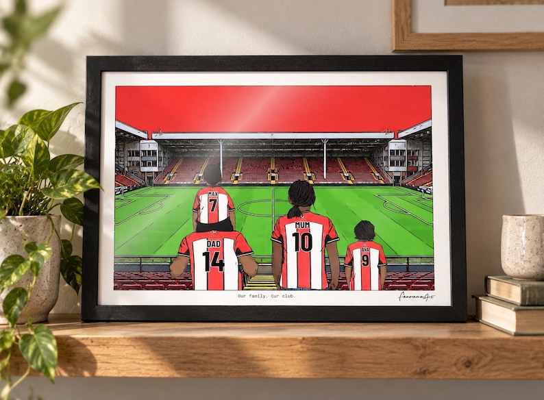 May include: A framed illustration of a family of four wearing red and white striped soccer jerseys with names and numbers on the back, standing in a stadium. The text "Our family. Our club." is printed at the bottom of the artwork.
