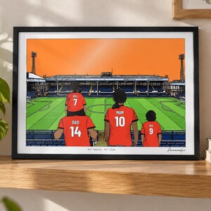May include: A framed illustration of a family of four wearing red soccer jerseys with names and numbers on the back, standing in a stadium. The jerseys are labeled DAD 14, MAX 7, MUM 10, and AVA 9. The text Our family. Our club. is printed below.