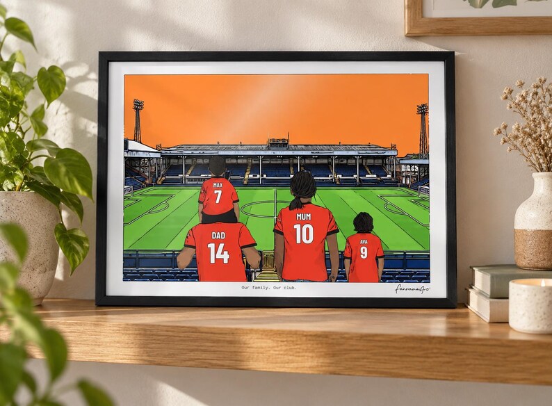 May include: A framed illustration of a family of four wearing red soccer jerseys with names and numbers on the back, standing in a stadium. The jerseys are labeled DAD 14, MAX 7, MUM 10, and AVA 9. The text Our family. Our club. is printed below.