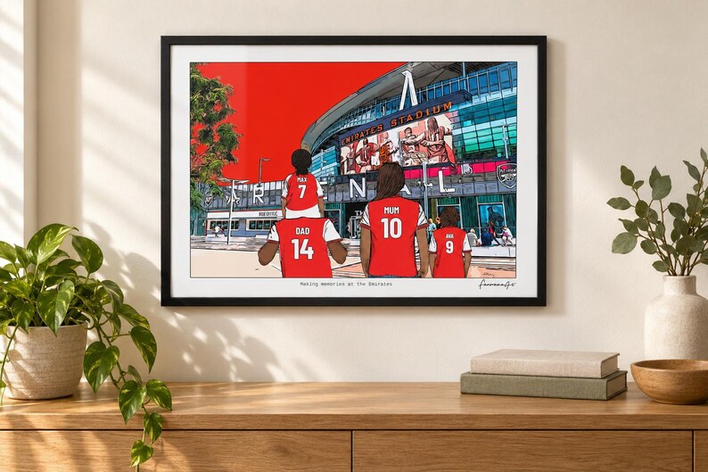 AI-created lifestyle mockup of a black framed Arsenal family print above a wooden console in a bright living room, with a plant and books.