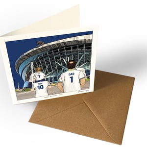 May include: A square greeting card featuring a cartoon illustration of a family walking toward a large stadium. The figures wear white jerseys with the text DAD 1, MUM 10, and IVY 7. The text Happy Birthday, Dad is printed at the bottom.