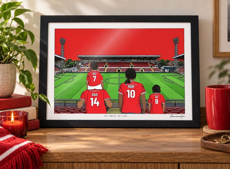 Pu&ograve; includere: Un'illustrazione incorniciata di una famiglia di quattro persone che indossa maglie da calcio rosse con nomi e numeri in uno stadio. Le maglie riportano le scritte Dad 14, Max 7, Mum 10 e Ana 9. Il testo Our family. Our club. &egrave; stampato in basso.