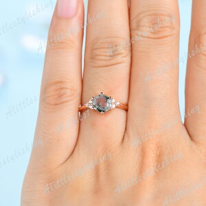 May include: A rose gold engagement ring with a hexagonal green gemstone and smaller clear gemstones on the band.