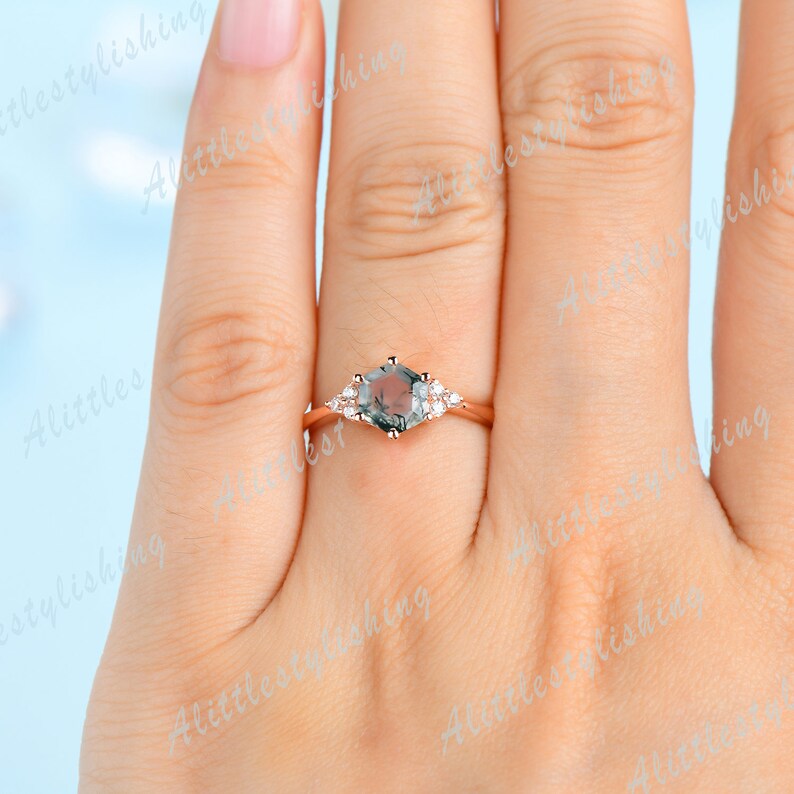 May include: A rose gold engagement ring with a hexagonal green gemstone and smaller clear gemstones on the band.