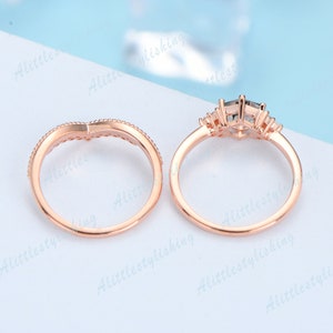 May include: Two rose gold rings with clear stones. The larger ring has a larger stone in the center with smaller stones on either side. The smaller ring has a delicate design.