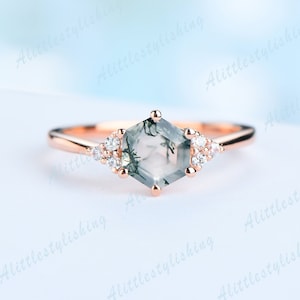 May include: A rose gold ring with a hexagonal green moss agate gemstone and small clear round accent stones.