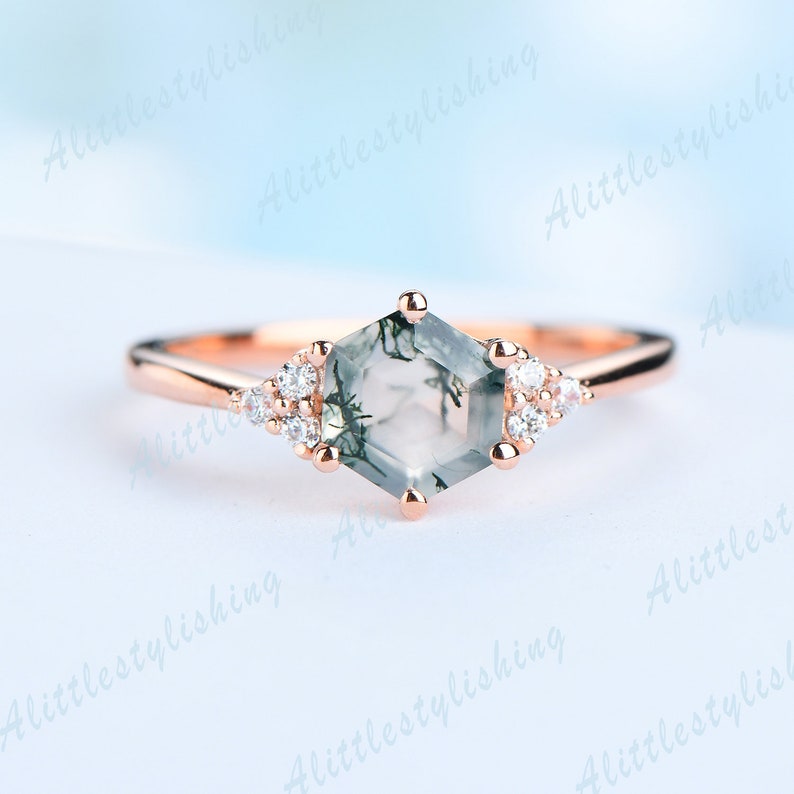 May include: A rose gold ring with a hexagonal green moss agate gemstone and small clear round accent stones.