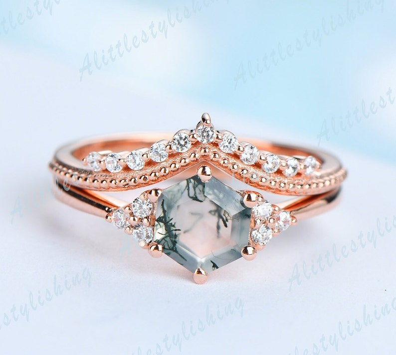 May include: A rose gold engagement ring set with a hexagonal green moss agate gemstone and a delicate band of smaller clear gemstones.