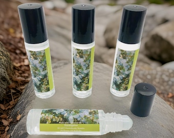 May include: Four clear glass roll-on bottles with black caps, filled with a light green liquid. The bottles are labeled "Eucalyptus" and "Made with Essential Oil". The bottles are sitting on a gray rock.