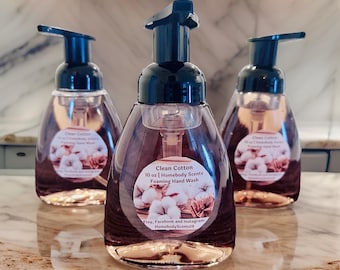 May include: Three clear plastic bottles of foaming hand wash with black pump tops. The center bottle has a label that reads "Clean Cotton 10 oz | Homebody Scents Foaming Hand Wash" and "Etsy, Facebook and Instagram: HomebodyScents18".