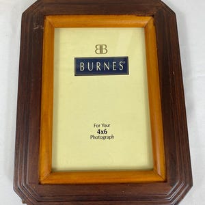 May include: Rectangular wooden picture frame with a dark brown exterior and a lighter brown interior border. The frame is designed for a 4x6 photograph and features the "BURNES" logo.