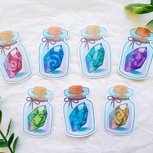 May include: Seven stickers of potion bottles with colorful crystals inside. Each bottle has a cork stopper and a ribbon tied around the neck. The crystals are various colors, including red, blue, green, and purple.