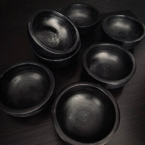 May include: A set of seven black ceramic bowls of varying sizes. The bowls are smooth and have a glossy finish.