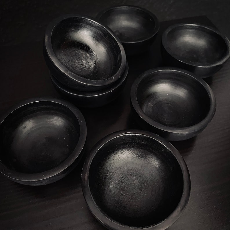 May include: A set of seven black ceramic bowls of varying sizes. The bowls are smooth and have a glossy finish.