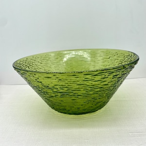 May include: A large, green glass bowl with a textured surface. The bowl is round and has a wide rim.