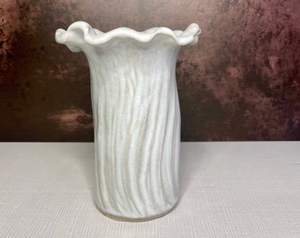 May include: White ceramic vase with a wavy, ruffled top and a textured, ribbed body.