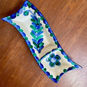 May include: A white ceramic serving dish with two sections. The dish is decorated with blue and green floral designs.