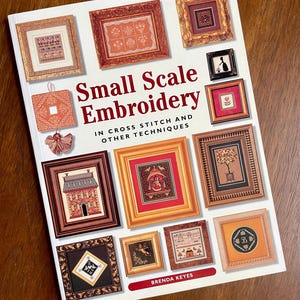 May include: A book titled "Small Scale Embroidery" in cross stitch and other techniques by Brenda Keyes. The cover features a variety of framed embroidery designs in various colors and styles.