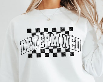 Op de afbeelding: Wit sweatshirt met een zwart geruit patroon en het woord "DETERMINED" in een vintage lettertype.
