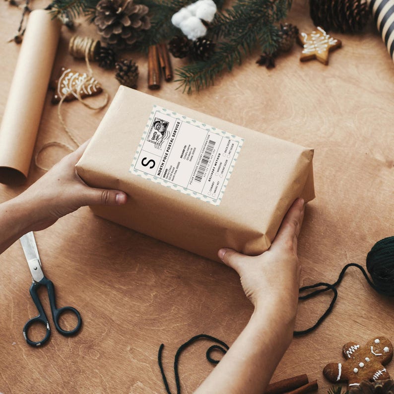 Hands holding a Christmas gift with a North Pole delivery sticker. Customizable design includes recipient name, address, and delivery method options like chimney or magic key.