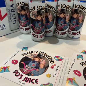 May include: Several custom-labeled beverage cans and stickers are displayed. The cans are white with a photo of two children and the text "Freshly Squeezed 90's Juice, 355 ml." The stickers have the same design. A box of Michelob Ultra beer is in the background.