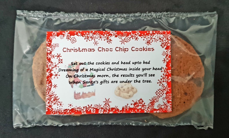 May include: A clear plastic bag containing two chocolate chip cookies with a red and white label that reads "Christmas Choc Chip Cookies" and a poem about dreaming of a magical Christmas.