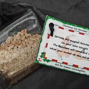 May include: A small clear bag filled with reindeer food, a Christmas Eve treat. The bag is tied with a black ribbon and has a tag attached that reads "Christmas Eve Reindeer Treat" and includes instructions for sprinkling the food on the lawn. The tag also says "Not for human consumption."