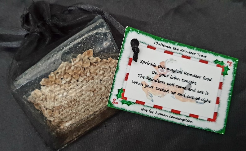 May include: A small clear bag filled with reindeer food, a Christmas Eve treat. The bag is tied with a black ribbon and has a tag attached that reads "Christmas Eve Reindeer Treat" and includes instructions for sprinkling the food on the lawn. The tag also says "Not for human consumption."